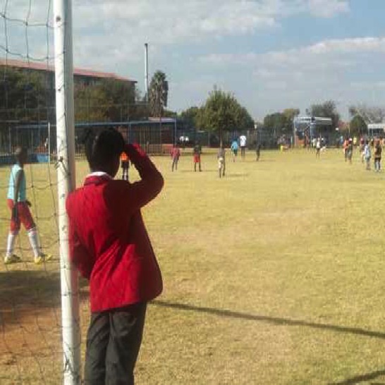 A girl watching boys play soccer.